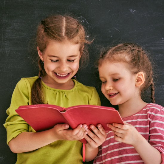 Back to school! Two happy cute industrious children indoors. Kids are learning in class on background of blackboard.